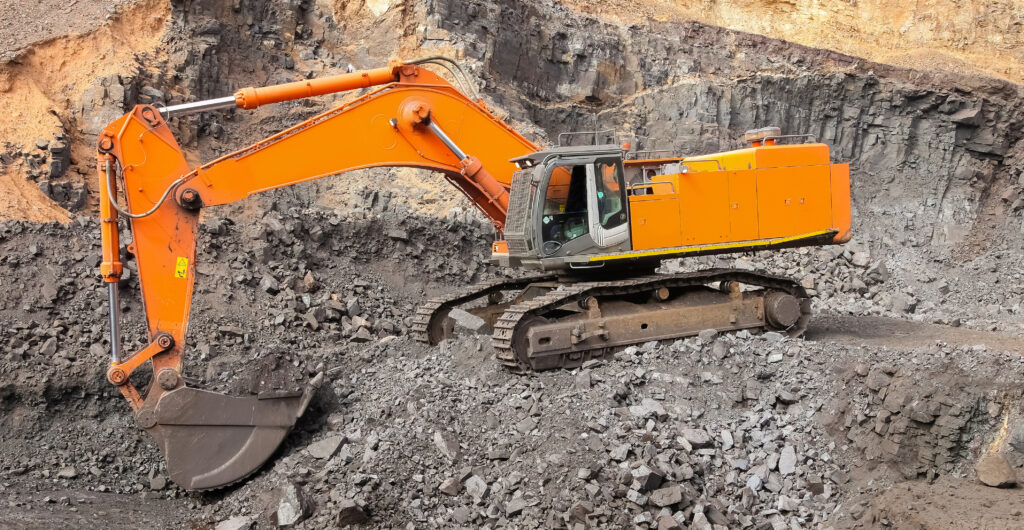 yellow excavator digging for ore rich rock in an open pit mine